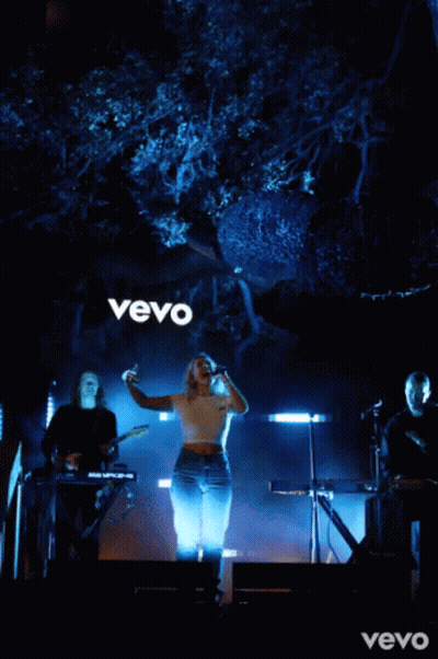 Woman Singing Into Microphone In Front Of Vevo Sign GIF