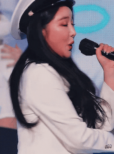 Woman Singing Into Microphone In Hat And White Jacket GIF