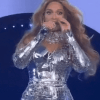 Woman Singing Into Microphone In Silver Dress GIF