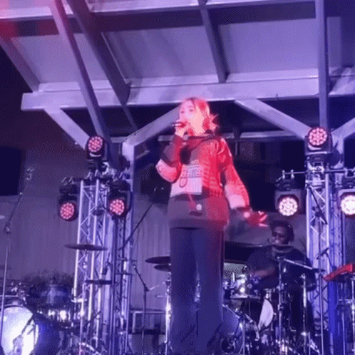 Woman Singing Into Microphone In Ugly Christmas Sweater GIF