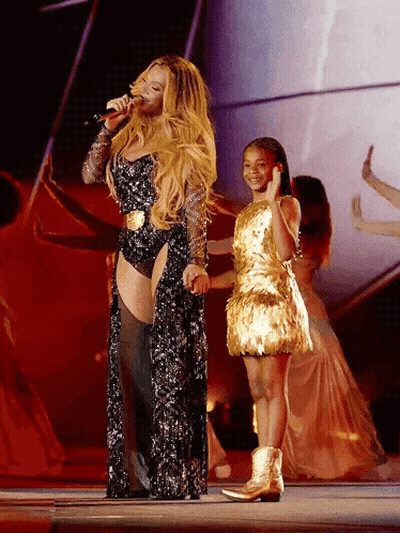 Woman Singing Into Microphone Next To Girl In Gold Dress GIF