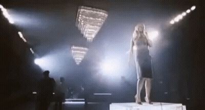 Woman Singing Into Microphone On Stage With Chandelier GIF