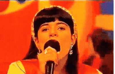 Woman Singing Into Microphone Orange Background GIF