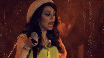 Woman Singing Into Microphone With Hat And Yellow Shirt GIF