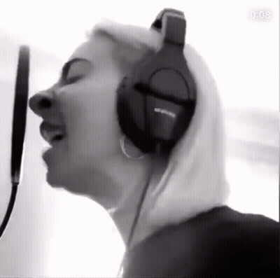Woman Singing Into Microphone With Headphones In Black And White GIF