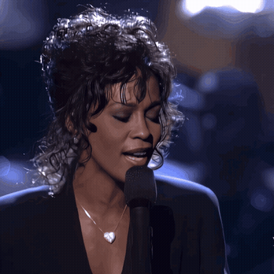Woman Singing Into Microphone With Heart Necklace GIF