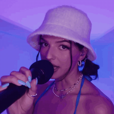 Woman Singing Into Microphone With White Hat And Blue Nails GIF