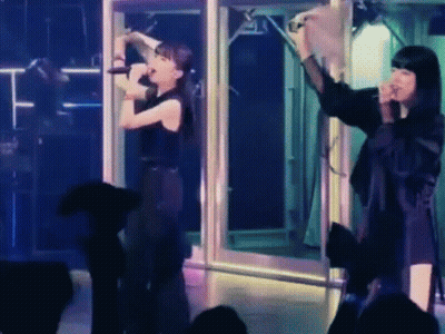 Woman Singing Into Microphone With Woman Behind GIF