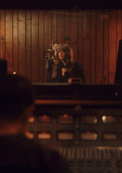 Woman Singing Into Microphone With X Necklace GIF