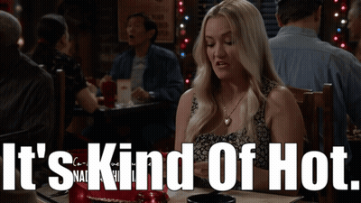 Woman Sits At Table Saying It's Kind Of Hot GIF
