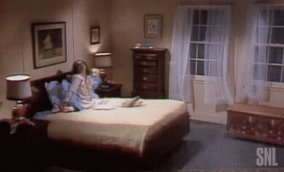 Woman Sits On Bed In Bedroom With SNL GIF