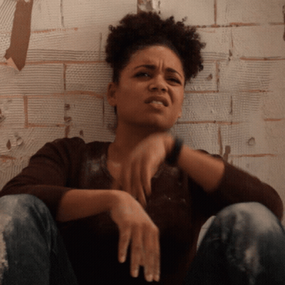 Woman Sitting Against Brick Wall GIF