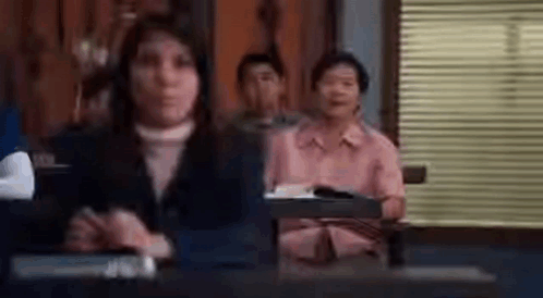 Woman Sitting At Desk In Front Of Group GIF