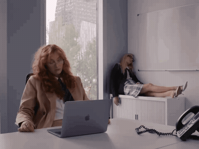 Woman Sitting At Desk With Apple Laptop And Phone GIF