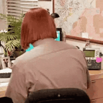 Woman Sitting At Desk With Computer And Phone GIF