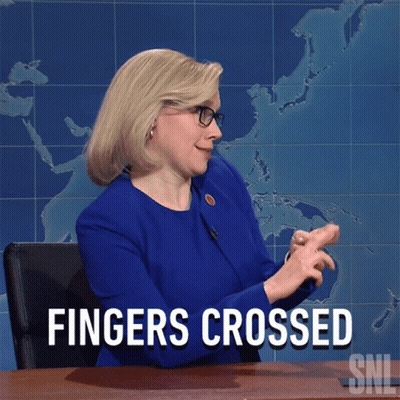 Woman Sitting At Desk With Hands Crossed Saying Fingers Crossed GIF