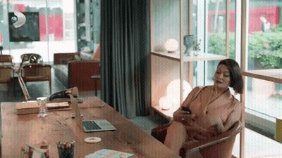 Woman Sitting At Desk With Laptop And Cell Phone GIF