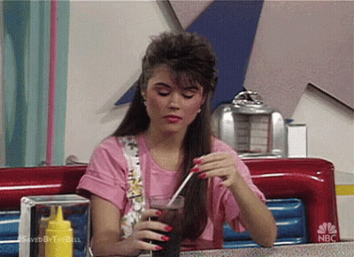 Woman Sitting At Diner Table Holding Soda GIF
