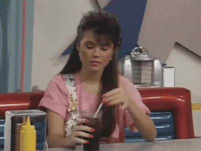 Woman Sitting At Diner Table Holding Soda GIF