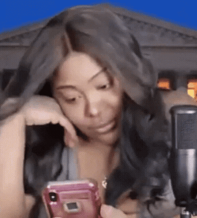 Woman Sitting At Microphone Looking At Phone GIF