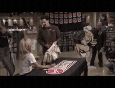Woman Sitting At Store Table With I Love You Sign GIF