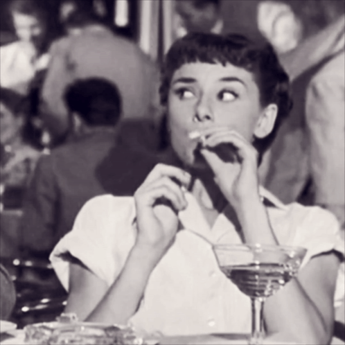 Woman Sitting At Table Drinking Martini And Smoking Cigarette GIF