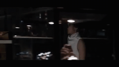Woman Sitting At Table In Dark Room GIF