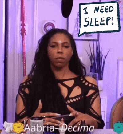 Woman Sitting At Table Saying I Need Sleep GIF