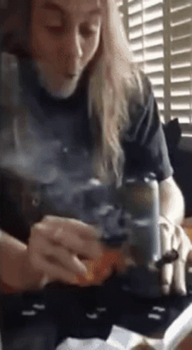 Woman Sitting At Table Smoking Cigarette While Reading Book GIF