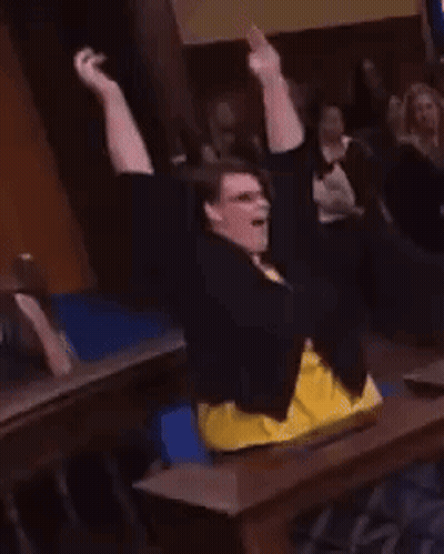 Woman Sitting At Table With Arms In Air GIF