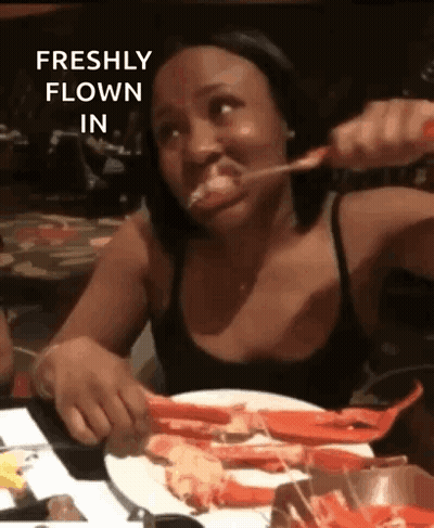 Woman Sitting At Table With Crab Legs And Spoon In Mouth GIF