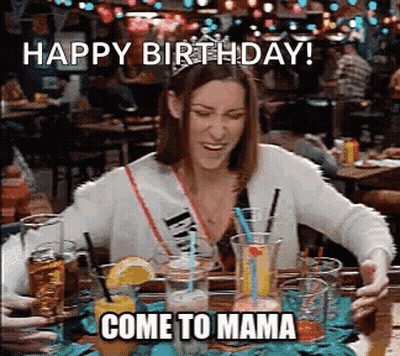Woman Sitting At Table With Drinks And Happy Birthday Come To Mama Sign GIF