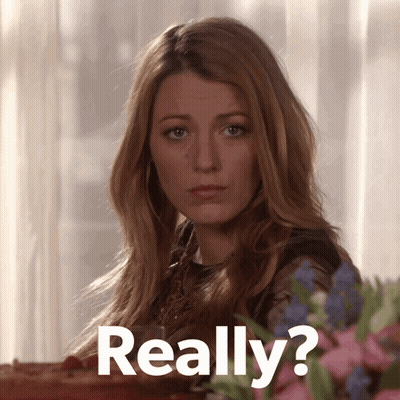 Woman Sitting At Table With Flowers Saying Really GIF