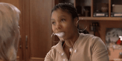 Woman Sitting At Table With Glass Of Milk In Mouth Talking To Another Woman GIF