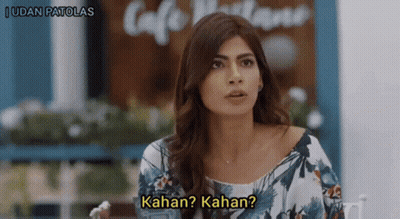 Woman Sitting At Table With Kahan Kahan Sign GIF