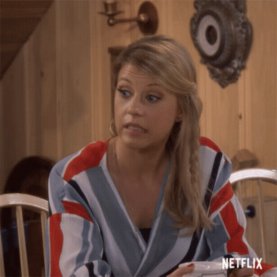Woman Sitting At Table With Netflix Logo On Shirt GIF