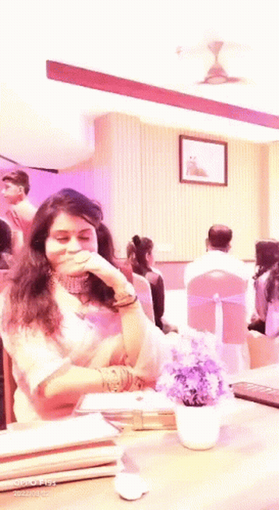 Woman Sitting At Table With Purple Flowers GIF