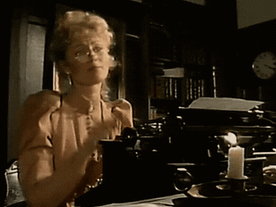 Woman Sitting At Table With Typewriter And Candle GIF