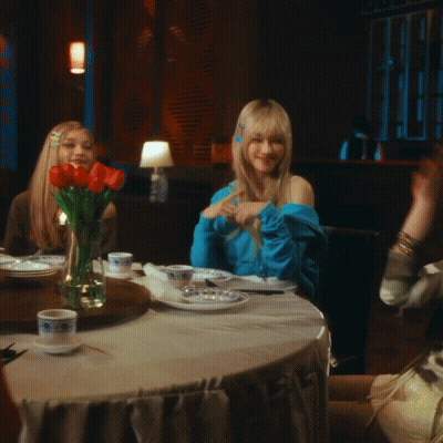 Woman Sitting At Table With Vase Of Flowers GIF