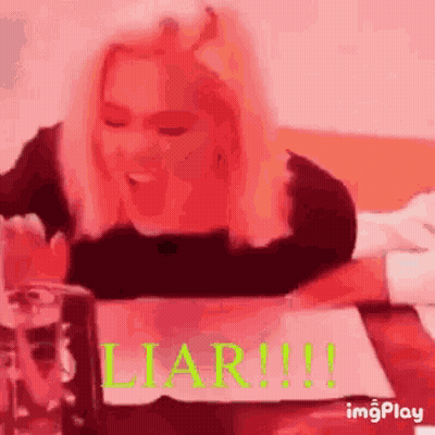 Woman Sitting At Table With Water And Liar Sign GIF