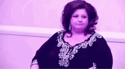 Woman Sitting By Purple Wall In Purple White Shirt GIF