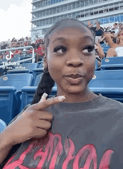Woman Sitting In Baseball Stands Pointing At Face GIF