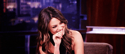 Woman Sitting In Chair Hand To Mouth Smiling GIF