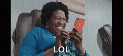 Woman Sitting In Chair Laughing At Phone GIF