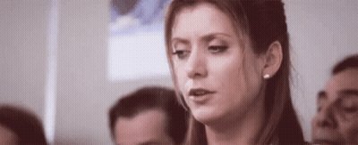 Woman Sitting In Crowd Looking At Camera GIF