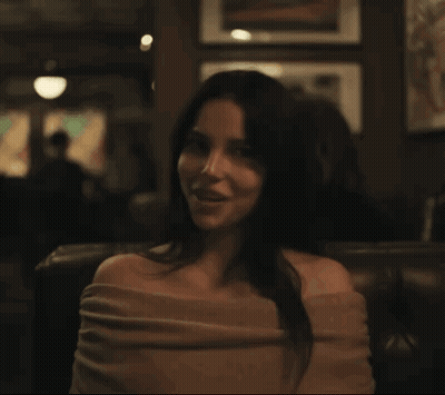 Woman Sitting In Dark Room With Wall Pictures GIF