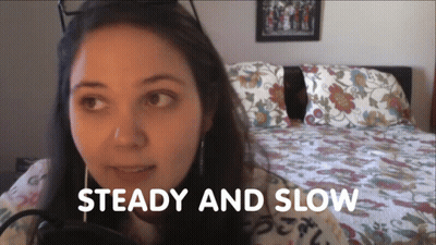 Woman Sitting In Front Of Bed Saying Steady And Slow GIF