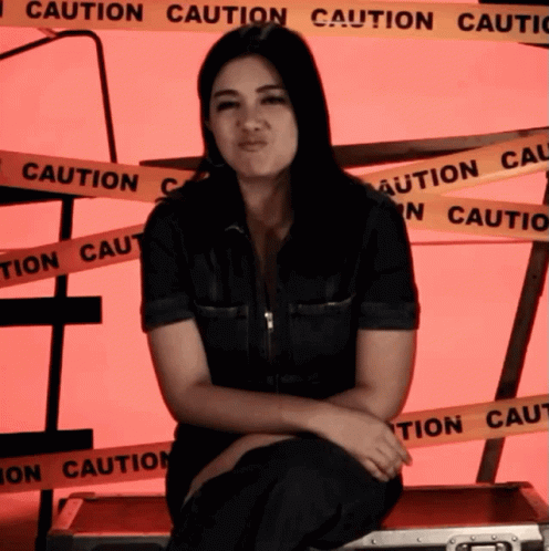 Woman Sitting In Front Of Caution Tape Wall GIF