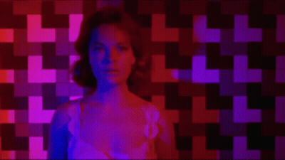 Woman Sitting In Front Of Checkered Wall With Purple And Red Lights GIF