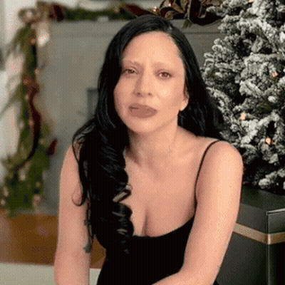Woman Sitting In Front Of Christmas Tree In Black Dress GIF